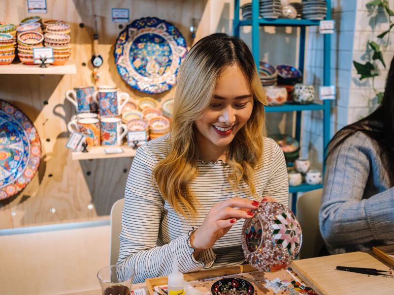 A girl smiles at a Turkish mosaic class